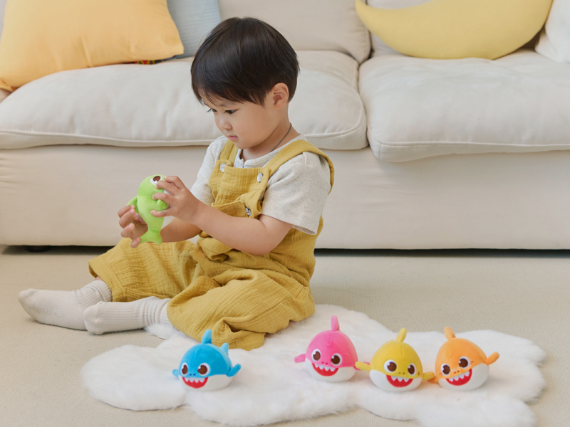 Child playing with Baby Shark Squishy Charm Plush toys on a rug