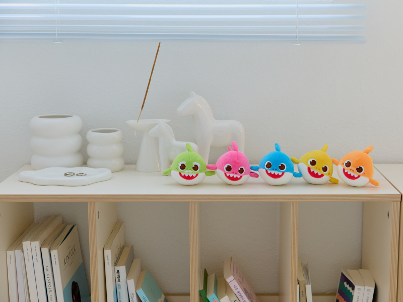 Five Baby Shark Squishy Charm Plush characters lined up on a shelf